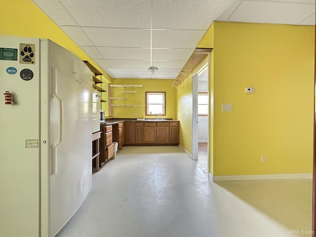 3930 E E Rd, Powers, MI 49874 - kitchen featuring freestanding refrigerator, a paneled ceiling, open shelves, concrete flooring, and brown cabinetry