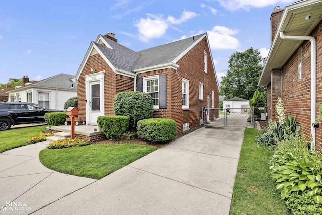 1857 Roslyn Rd, Grosse Pointe Woods, MI 48236 - view of side of home with brick siding, a gate, a shingled roof, a chimney, and concrete driveway