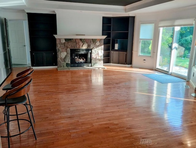 2308 S River Rd, Beaverton, MI 48612 - unfurnished living room featuring ornamental molding, hardwood / wood-style floors, a stone fireplace, and a tray ceiling