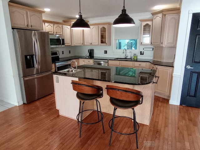 2308 S River Rd, Beaverton, MI 48612 - kitchen with stainless steel appliances, a center island with sink, glass insert cabinets, wood-type flooring, and decorative light fixtures