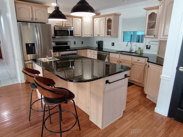 2308 S River Rd, Beaverton, MI 48612 - kitchen featuring appliances with stainless steel finishes, an island with sink, glass insert cabinets, light wood-type flooring, and a breakfast bar