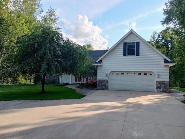 2308 S River Rd, Beaverton, MI 48612 - view of front of home featuring a garage, driveway, a front lawn, and stone siding