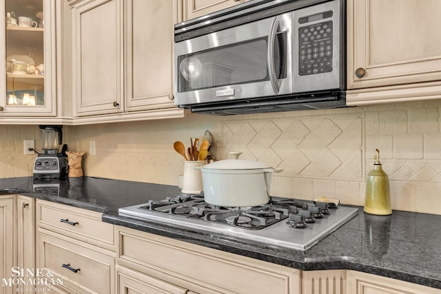3325 Saint Andrews Dr, Port Huron, MI 48060 - kitchen featuring appliances with stainless steel finishes, decorative backsplash, cream cabinets, and glass insert cabinets
