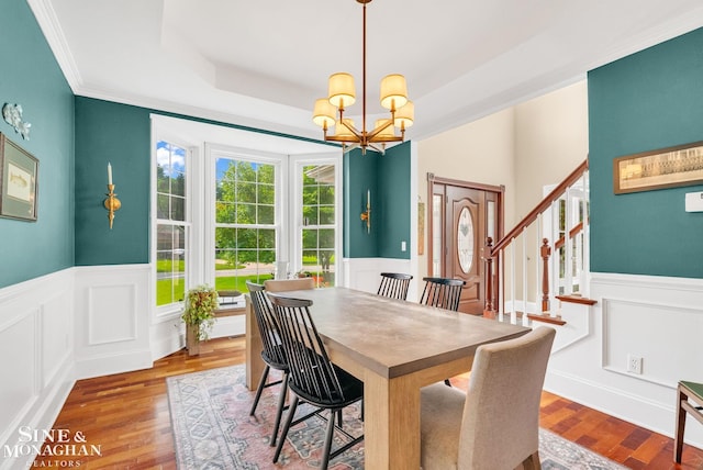 3325 Saint Andrews Dr, Port Huron, MI 48060 - dining area with a chandelier, a wainscoted wall, wood finished floors, a decorative wall, and stairs