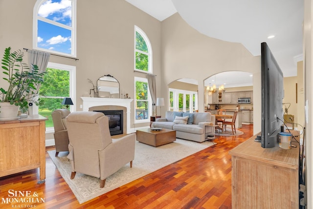 3325 Saint Andrews Dr, Port Huron, MI 48060 - living room featuring a towering ceiling, a chandelier, arched walkways, a glass covered fireplace, and light wood-style floors