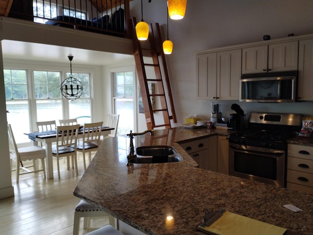 11374 S Shore Dr, Lake, MI 48632 - kitchen with stainless steel appliances, a towering ceiling, dark stone countertops, pendant lighting, and a chandelier