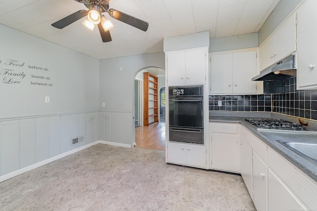 413 N Oakley St, Saginaw, MI 48602 - kitchen featuring black oven, a warming drawer, stainless steel gas stovetop, arched walkways, and under cabinet range hood