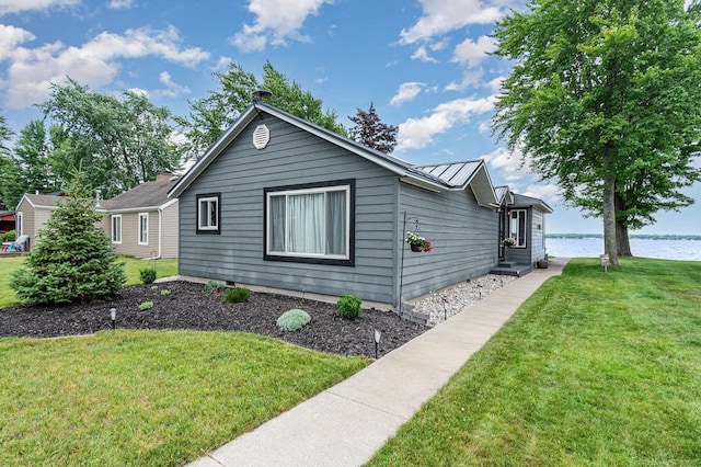 319 Old Trail Dr, Houghton Lake, MI 48629 - view of side of property with a lawn, a water view, a standing seam roof, and a metal roof