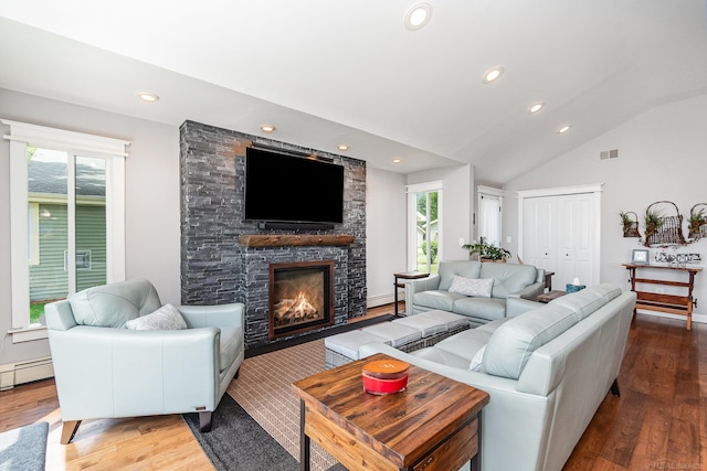 319 Old Trail Dr, Houghton Lake, MI 48629 - living room with wood finished floors, vaulted ceiling, recessed lighting, a stone fireplace, and a baseboard heating unit