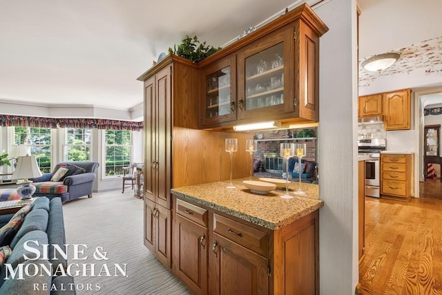 28 Hampton Rd, Grosse Pointe Shores, MI 48236 - kitchen featuring stainless steel gas stove, open floor plan, glass insert cabinets, brown cabinets, and ornamental molding