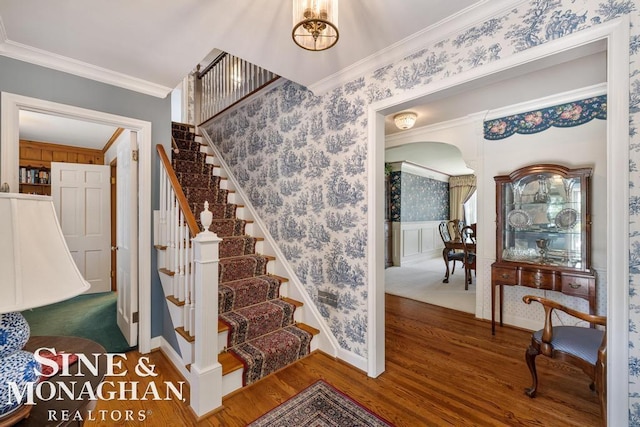 28 Hampton Rd, Grosse Pointe Shores, MI 48236 - staircase featuring crown molding, wood finished floors, wallpapered walls, arched walkways, and wainscoting
