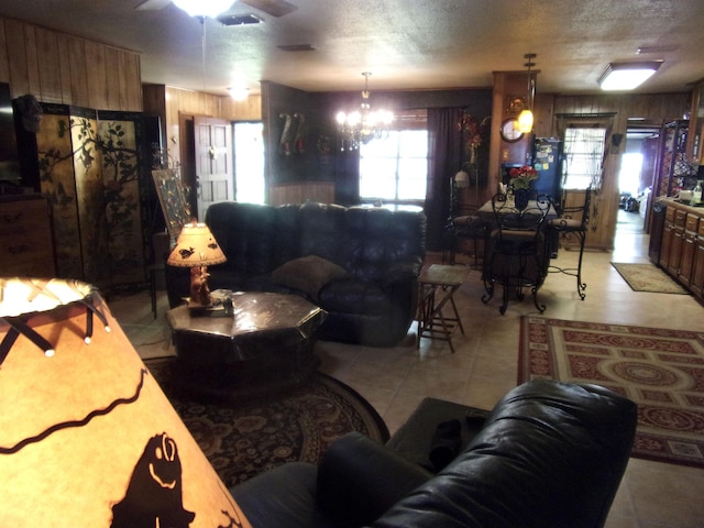 living room with wooden walls, ceiling fan with notable chandelier, and a textured ceiling