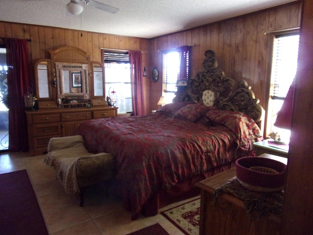 bedroom with a textured ceiling, multiple windows, wooden walls, and ceiling fan