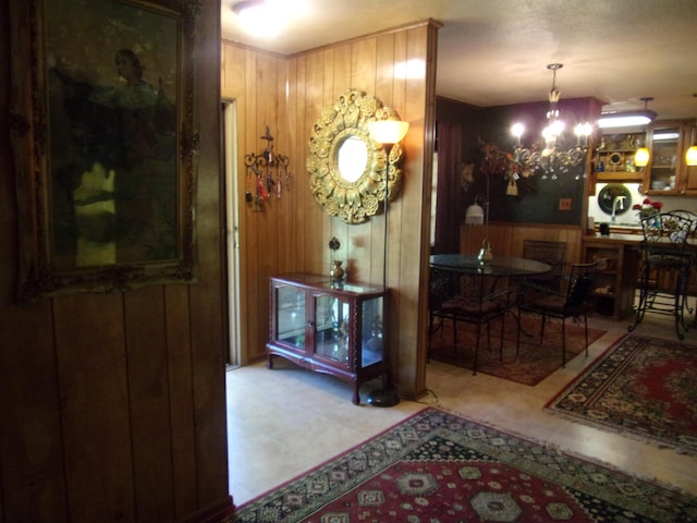 interior space with a chandelier, light tile patterned floors, and wooden walls