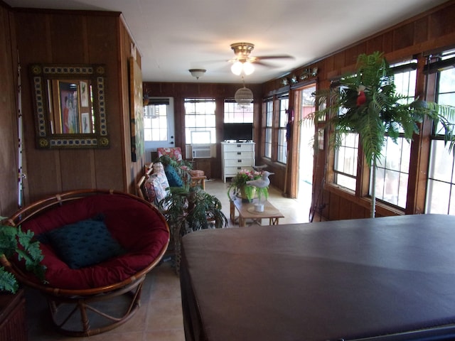 tiled dining room featuring cooling unit, ceiling fan, a healthy amount of sunlight, and wood walls