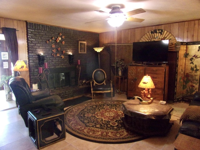 living room with wood walls, ceiling fan, and light tile patterned floors