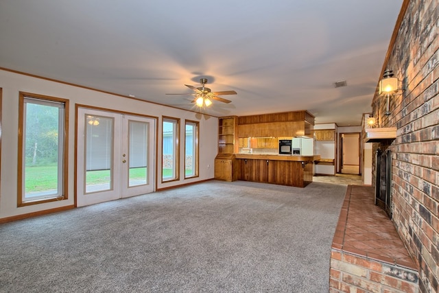 unfurnished living room with carpet, ornamental molding, brick wall, ceiling fan, and a fireplace