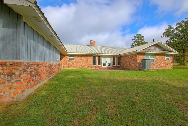 rear view of property featuring cooling unit and a lawn