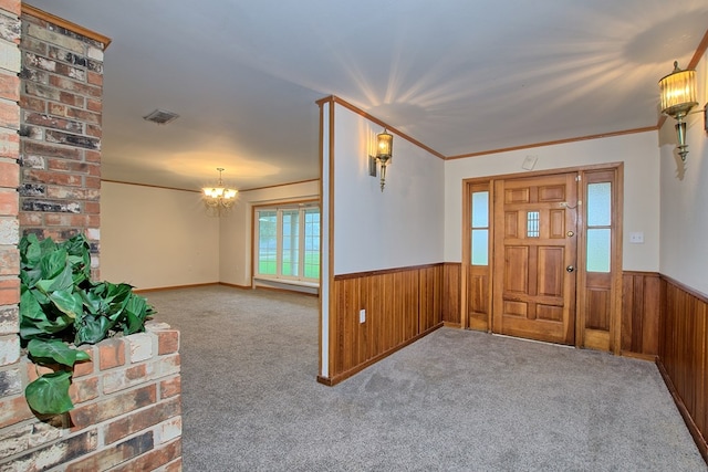 carpeted foyer featuring a notable chandelier, wood walls, and crown molding