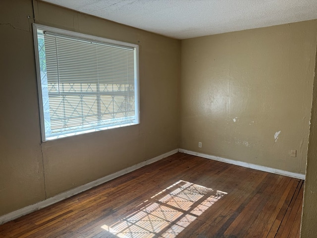 empty room with a textured ceiling and dark wood-type flooring