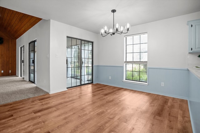 463 Allen Dr, Pollok, TX 75969 - unfurnished dining area featuring a chandelier, light wood finished floors, wainscoting, wooden walls, and vaulted ceiling
