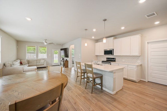 kitchen featuring appliances with stainless steel finishes, a sink, white cabinetry, backsplash, and visible vents