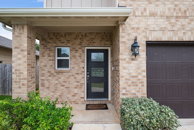 doorway to property with brick siding, a garage, and board and batten siding