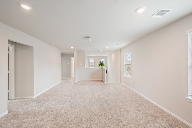 unfurnished room with baseboards, light carpet, recessed lighting, and visible vents