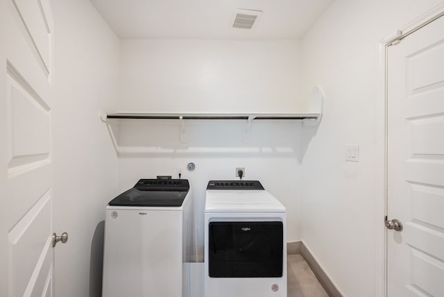 clothes washing area featuring baseboards, visible vents, laundry area, and washer and dryer