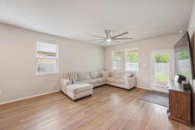 living room featuring a ceiling fan, baseboards, and light wood-type flooring