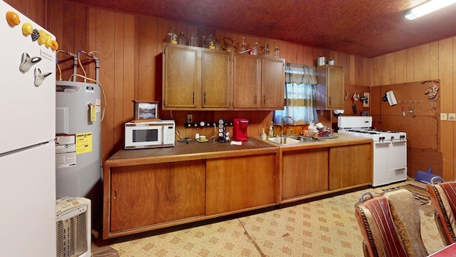 kitchen featuring white appliances, wooden walls, water heater, and sink