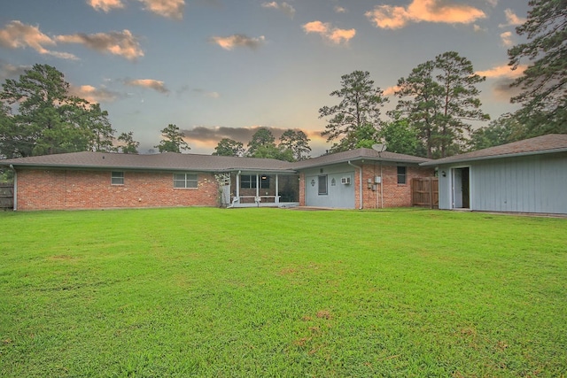 back house at dusk featuring a yard