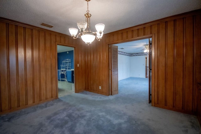 empty room with crown molding, wooden walls, carpet, and a chandelier