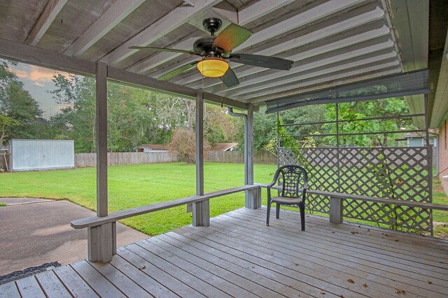 wooden terrace featuring ceiling fan and a yard