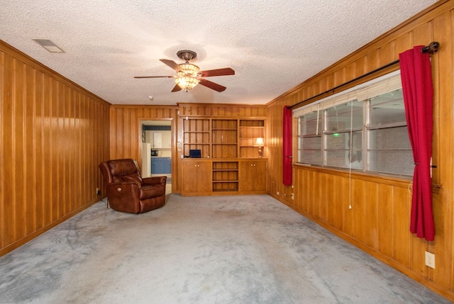 unfurnished room with light carpet, a textured ceiling, and wood walls