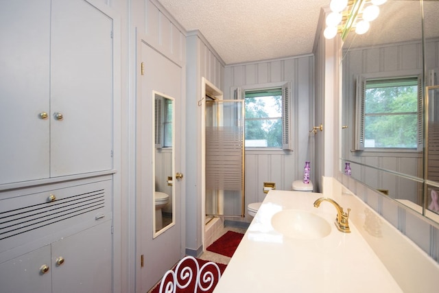 bathroom with vanity, crown molding, toilet, a textured ceiling, and an enclosed shower