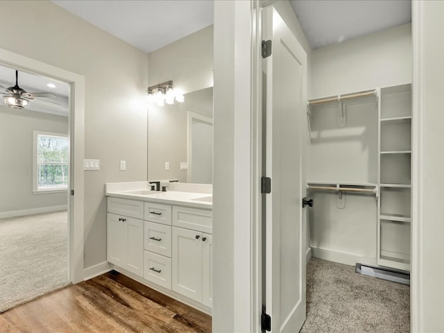 bathroom featuring a walk in closet, ceiling fan, baseboards, and a sink