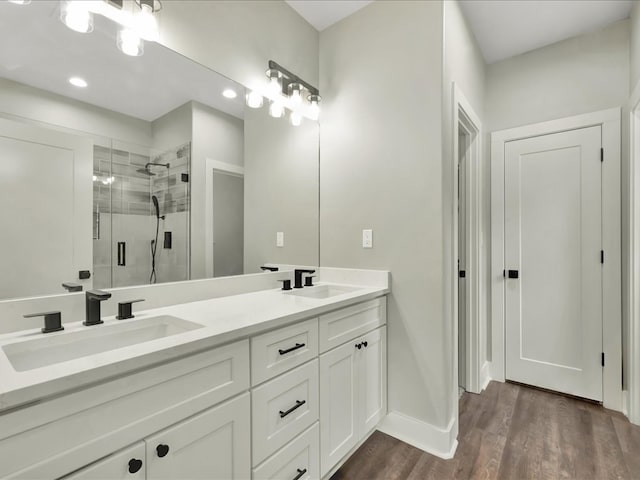 bathroom featuring baseboards, wood finished floors, a stall shower, and a sink