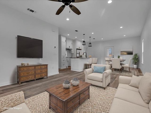 living room featuring sink, light hardwood / wood-style flooring, and ceiling fan