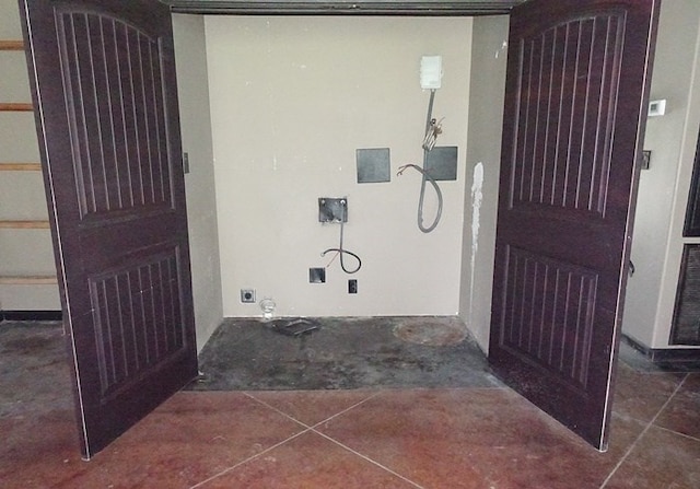 interior space with dark tile patterned floors and hookup for an electric dryer