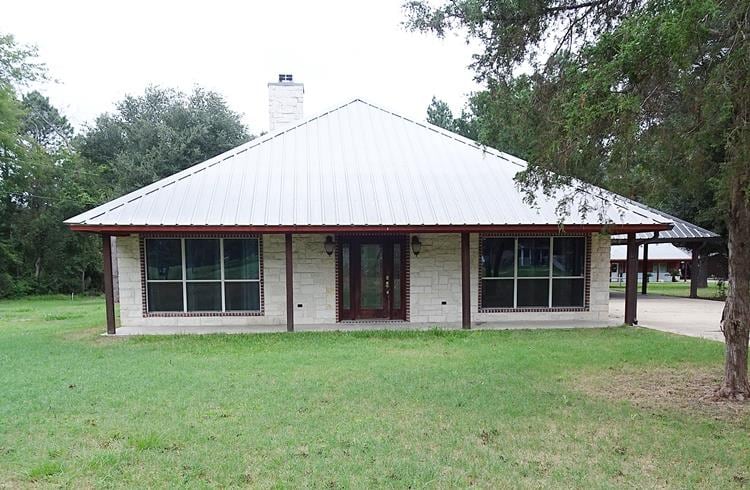 rear view of property featuring a carport and a yard