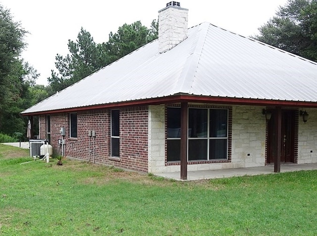 view of side of home featuring a lawn and central AC