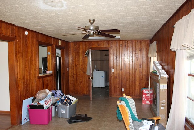 interior space featuring washer / dryer, a ceiling fan, and wood walls