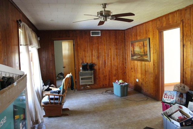 interior space featuring visible vents, wood walls, heating unit, and ceiling fan