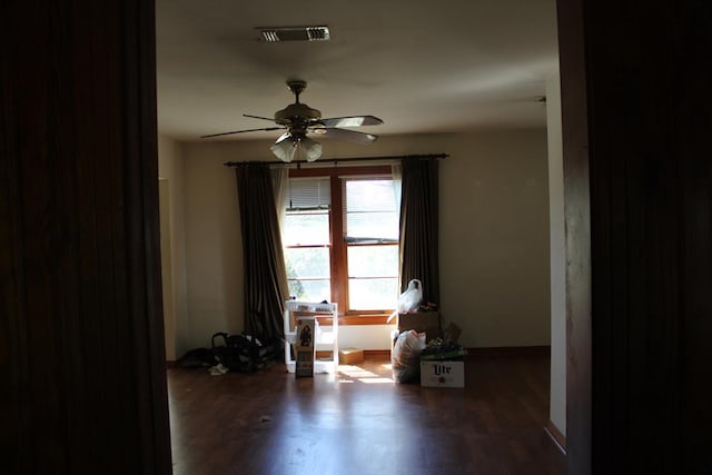 empty room with a ceiling fan, visible vents, baseboards, and wood finished floors