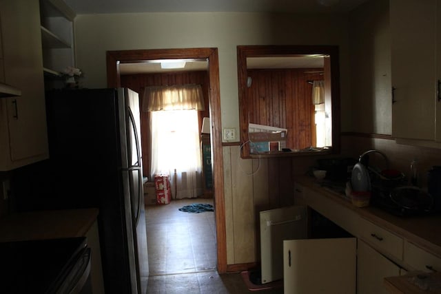 kitchen featuring wooden walls, stove, and white cabinets