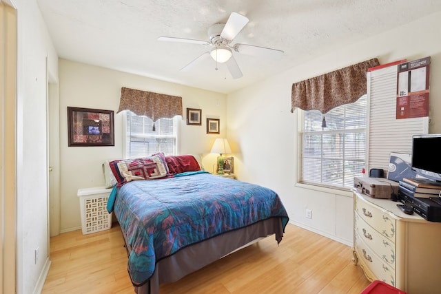 bedroom featuring a textured ceiling, baseboards, light wood-style flooring, and a ceiling fan