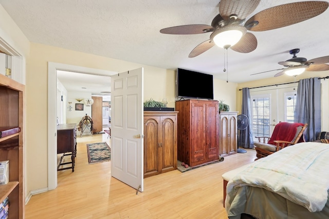 bedroom with light wood-type flooring, access to outside, a textured ceiling, and french doors