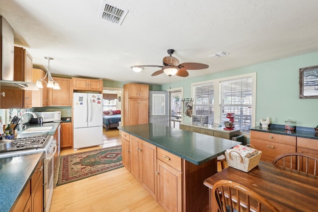 kitchen featuring light wood-type flooring, white appliances, dark countertops, and visible vents