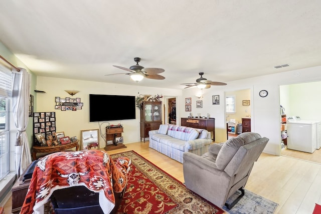 living area featuring light wood-style floors, plenty of natural light, visible vents, and washer and clothes dryer